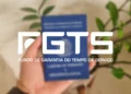Carteira de trabalho desfocada ao fundo com destaque para a logo do FGTS