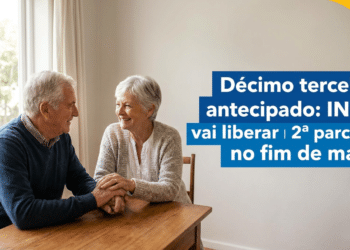 Casal de idosos sentados à mesa de madeira, sorrindo e de mãos dadas, com texto sobre 2ª parcela do 13º do INSS