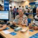 Dois idosos sorridentes contam notas de dinheiro ao serem atendidos por funcionária da Caixa em agência bancária