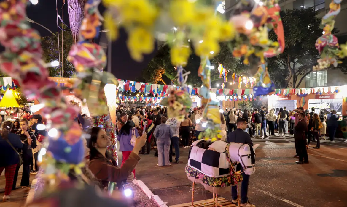 Festa junina em capital brasileira reúne multidão na véspera de feriado de 24 de junho Pessoas de diferentes idades celebram festa junina à noite com bandeirolas coloridas e boi decorado em destaque