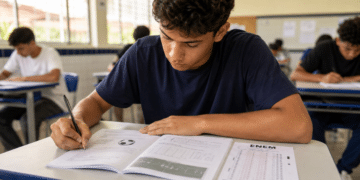 Jovem faz prova do ENEM, caderno mostra questão com bola de futebol e campo desenhado