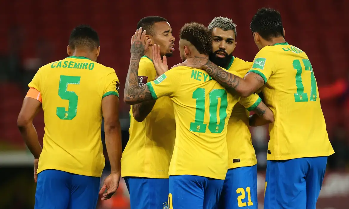Seleção Brasileira comemora gol em partida das Eliminatórias Jogadores da seleção brasileira com uniformes amarelos celebram gol juntos no gramado