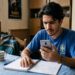 Estudante de camisa azul do Brasil olha celular com expressão séria ao lado de calendário marcando prazo do Enem