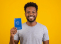 Jovem segura carteira de trabalho brasileira sorrindo com fundo amarelo.