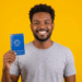 Jovem segura carteira de trabalho brasileira sorrindo com fundo amarelo.