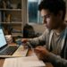 Jovem utiliza cartão e celular para pagar taxa do Enem 2026 em notebook, rodeado de livros e anotações