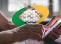 Mãos de pessoa idosa usando o aplicativo Meu INSS no celular para contestar descontos indevidos