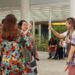 Cinco pessoas trocam sinais em Libras em área aberta, mochilas e roupas coloridas