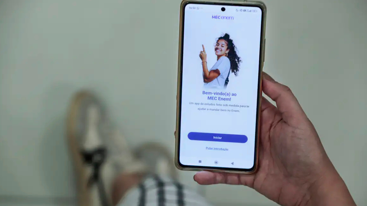 Aplicativo MEC Enem oferece recursos gratuitos de estudo para o exame Pessoa segurando celular com aplicativo MEC Enem aberto para preparação de estudantes.