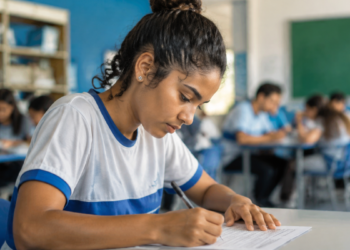 Jovem estudante preenchendo inscrição para curso de qualificação profissional do Pronatec em ambiente escolar.