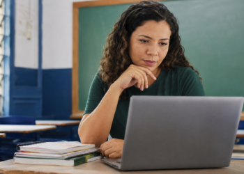 Professora utiliza notebook em sala de aula durante formação sobre inteligência artificial para educadores.