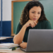Professora utiliza notebook em sala de aula durante formação sobre inteligência artificial para educadores.