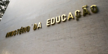 Fachada do prédio do Ministério da Educação, com o nome do órgão em letras douradas aplicadas sobre parede de revestimento claro, vista em ângulo de baixo para cima.