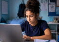 Estudante se preparando para o Enem 2026 com notebook e materiais de estudo em ambiente residencial.