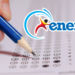 Mão segura lápis azul preenchendo folha de respostas do ENEM com logo do exame em destaque.
