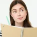Você escreve “click” ou “clique”? Entenda a diferença e evite erro de português 10 Mulher segurando caderno e caneta com expressão de dúvida.