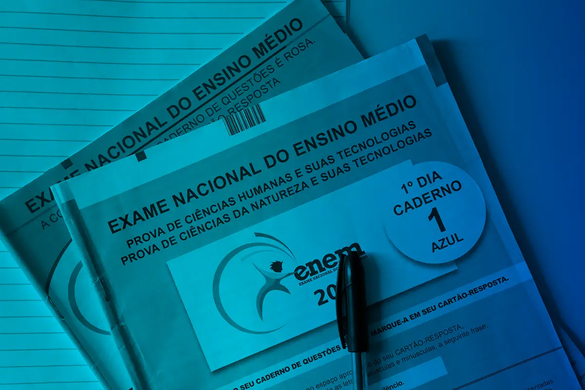 Novo Guia do Enem. Duas provas do Enem e caneta encima da mesa.