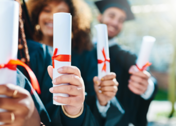 Formandos celebram conquista com certificados em cerimônia ao ar livre.