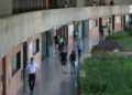 Pessoas caminhando por corredor de universidade.