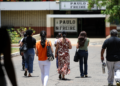 Pessoas caminham em direção a uma escola, representando participantes da Prova Nacional Docente 2026.