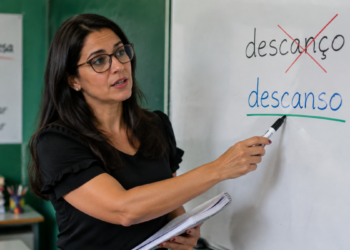 Professora corrigindo no quadro branco as palavras “descanço” e “descanso”, destacando a grafia correta da palavra.