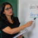 Como se escreve: descanço ou descanso? Confira o que diz a gramática sobre a palavra 11 Professora corrigindo no quadro branco as palavras “descanço” e “descanso”, destacando a grafia correta da palavra.