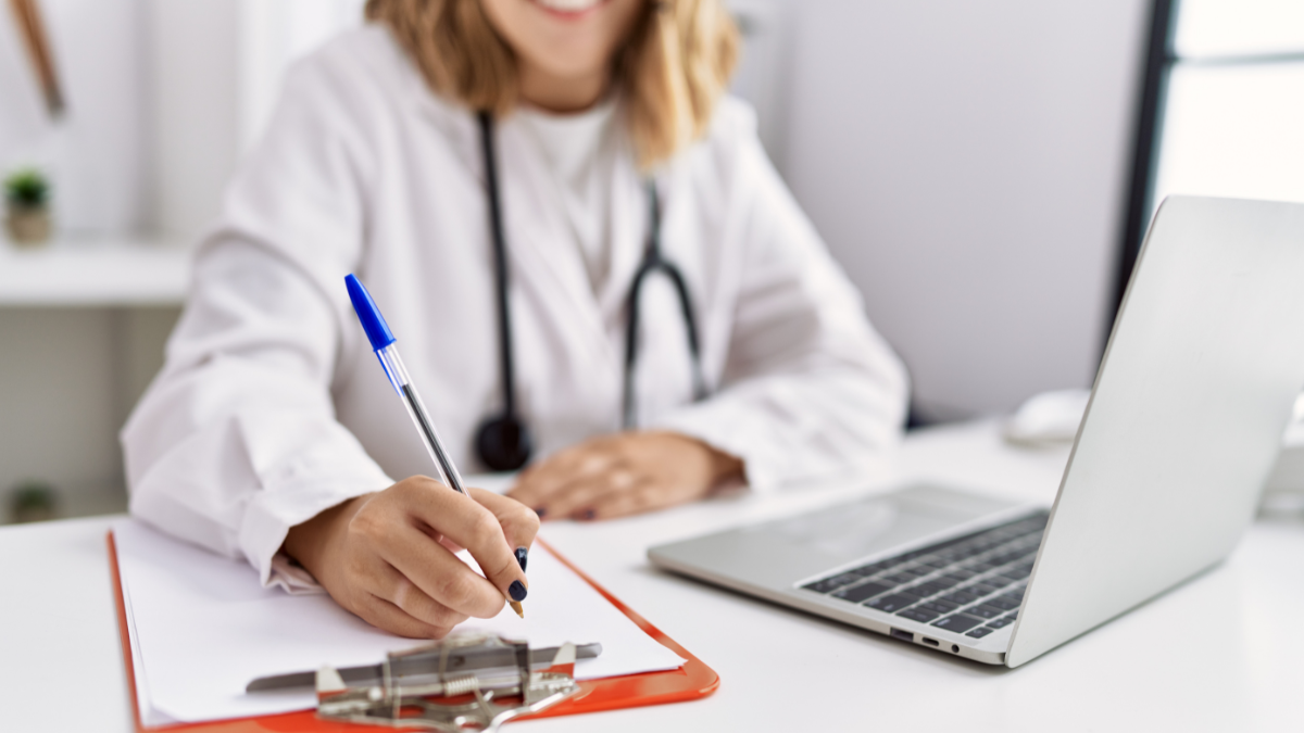 Reaplicação do Enamed 2026 - Prazo para solicitar nova prova de formação médica Médica preenchendo documento em mesa de trabalho representando o prazo para solicitar a reaplicação do Enamed 2026.