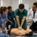 Residentes em saúde participam de treinamento prático com boneco de simulação e orientação de um professor.