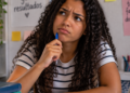 Estudante com expressão de dúvida durante estudo de português sobre o uso correto de pode vir e pode vim.