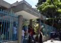 Candidatos chegando ao portão de um colégio estadual em dia de aplicação de prova
