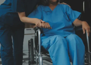 Quer se atualizar em enfermagem? Curso online aborda cuidados na assistência pós-operatória; veja como se inscrever 5 Profissional de enfermagem auxilia paciente em cadeira de rodas durante atendimento pós-operatório.