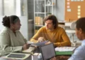 Supervisão Pedagógica: curso online de 80 horas ensina como atuar na gestão educacional 2 Profissionais reunidos em ambiente escolar analisam documentos e discutem estratégias de gestão e supervisão pedagógica.