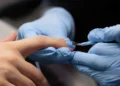 Do soft gel à fibra de vidro: curso reúne 39 conteúdos sobre alongamento de unhas 11 Profissional aplica esmalte azul em unha durante procedimento de alongamento e cuidados de manicure.