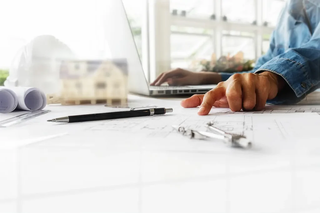 Profissional analisa uma planta arquitetônica, representando o curso online de ArchiCAD da Bizu e o aprendizado em modelagem 3D e projetos.