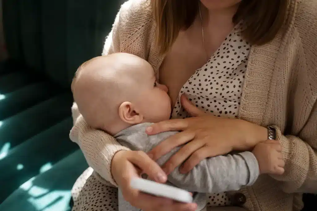 Mãe amamenta bebê em imagem relacionada aos cuidados com a amamentação e à rotina materna.