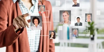 Profissional de Recursos Humanos interage com uma interface digital que apresenta perfis de colaboradores, representando a gestão de talentos e as metodologias ágeis.