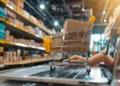 Carrinho de compras sobre notebook em ambiente de varejo representa curso online da Bizu sobre atendimento, vendas e fidelização de clientes.